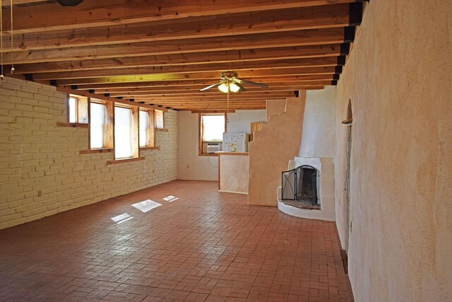 unfurnished living room featuring beamed ceiling, brick wall, cooling unit, and ceiling fan