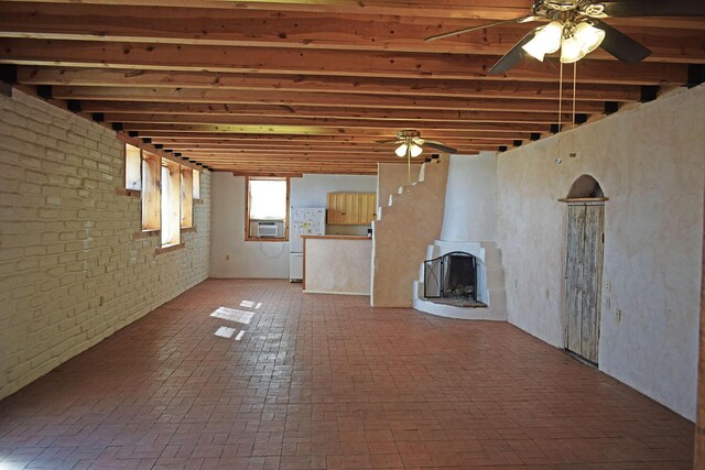 basement featuring ceiling fan, cooling unit, white fridge, brick wall, and a wood stove