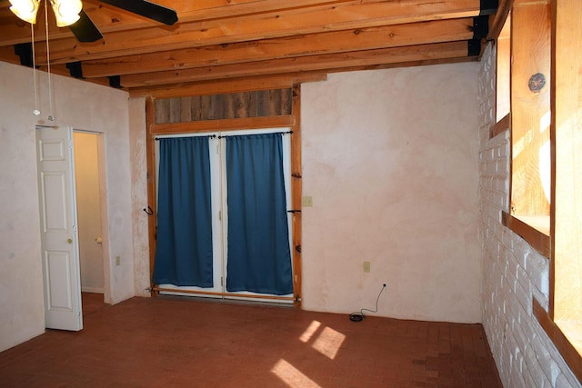 empty room featuring beamed ceiling and ceiling fan