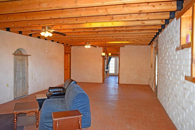 unfurnished living room with beamed ceiling and ceiling fan with notable chandelier