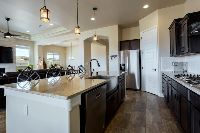 kitchen with sink, appliances with stainless steel finishes, a kitchen island with sink, and hanging light fixtures