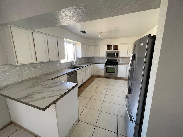 10613 Benavides Rd SW, Albuquerque, NM 87121 - kitchen with appliances with stainless steel finishes, a peninsula, a sink, backsplash, and light stone countertops
