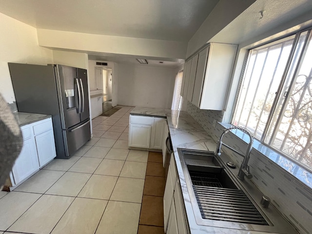 10613 Benavides Rd SW, Albuquerque, NM 87121 - kitchen with stainless steel refrigerator with ice dispenser, white cabinets, tasteful backsplash, light tile patterned flooring, and a sink