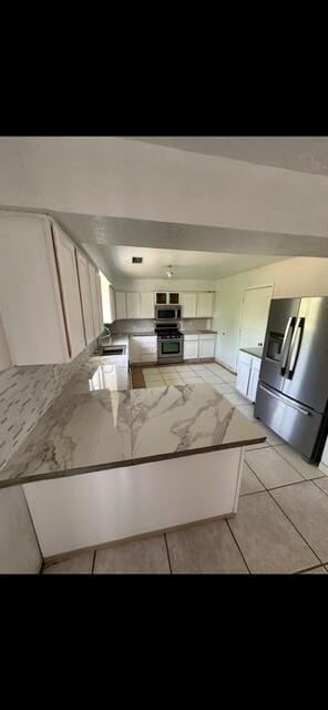 10613 Benavides Rd SW, Albuquerque, NM 87121 - kitchen with appliances with stainless steel finishes, a peninsula, a sink, light tile patterned flooring, and white cabinetry