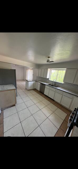 10613 Benavides Rd SW, Albuquerque, NM 87121 - kitchen with dishwasher, light tile patterned floors, a sink, and range with gas cooktop