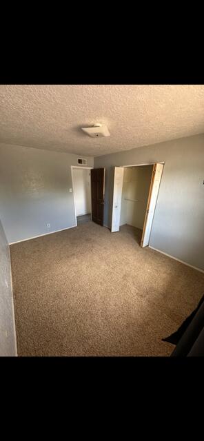 10613 Benavides Rd SW, Albuquerque, NM 87121 - unfurnished bedroom featuring light carpet and a textured ceiling