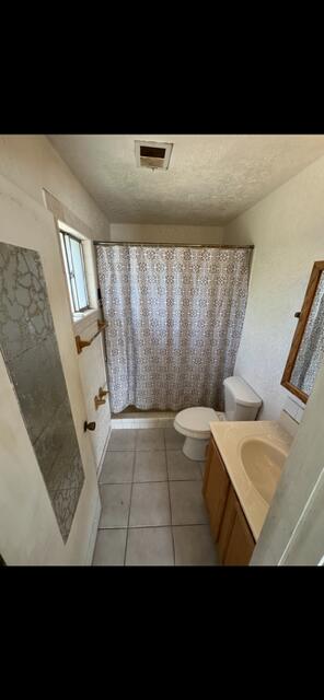 10613 Benavides Rd SW, Albuquerque, NM 87121 - bathroom featuring toilet, vanity, tile patterned floors, and shower / bath combo