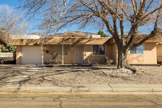 single story home featuring a garage, driveway, a shingled roof, and stucco siding