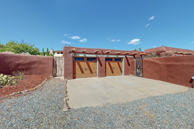 exterior space featuring a garage, gravel driveway, fence, and a gate