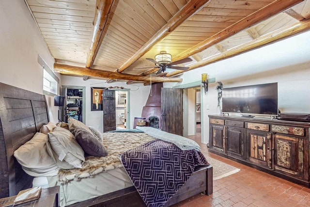 bedroom featuring brick floor, wood ceiling, a walk in closet, and beamed ceiling