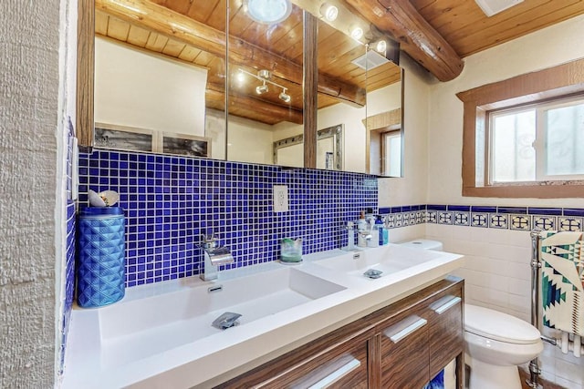 bathroom featuring tile walls, toilet, wood ceiling, a sink, and beamed ceiling