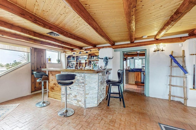 bar featuring brick floor, wood ceiling, beamed ceiling, and a dry bar