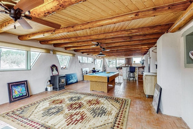 playroom with brick floor, plenty of natural light, wood ceiling, a wood stove, and beamed ceiling