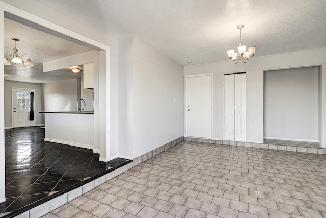 interior space featuring a sink, a textured ceiling, baseboards, and a notable chandelier