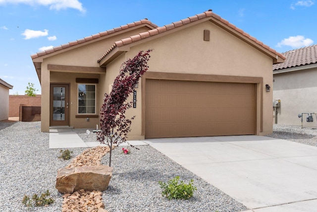 view of front facade with an attached garage, driveway, fence, and stucco siding