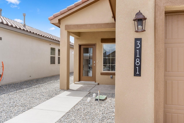 entrance to property featuring a tile roof and stucco siding