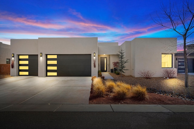 view of front of house with a garage, concrete driveway, and stucco siding