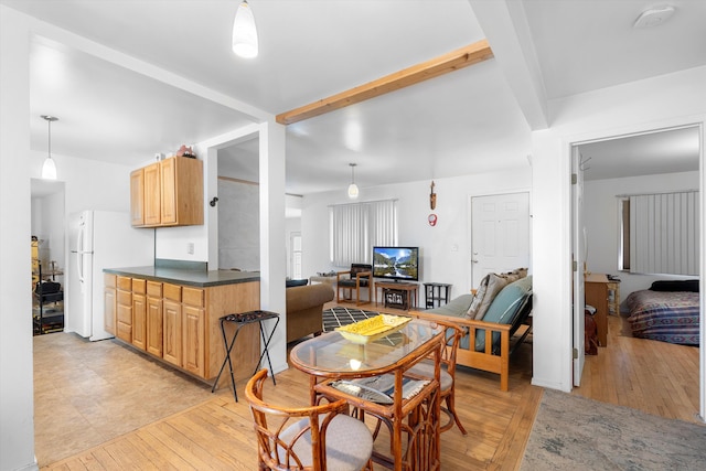 dining space featuring beamed ceiling and light wood-type flooring