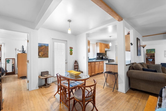 dining space featuring beamed ceiling and light hardwood / wood-style floors