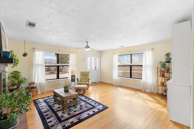 living area with light wood-style floors, visible vents, and a fireplace