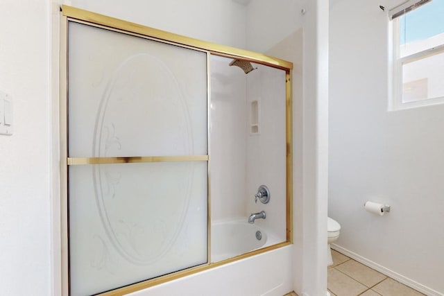 bathroom with tile patterned flooring, shower / bath combination with glass door, and toilet