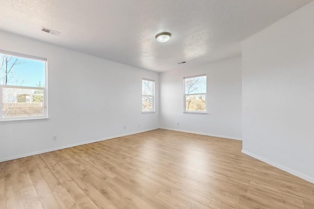 empty room featuring a textured ceiling and light hardwood / wood-style floors