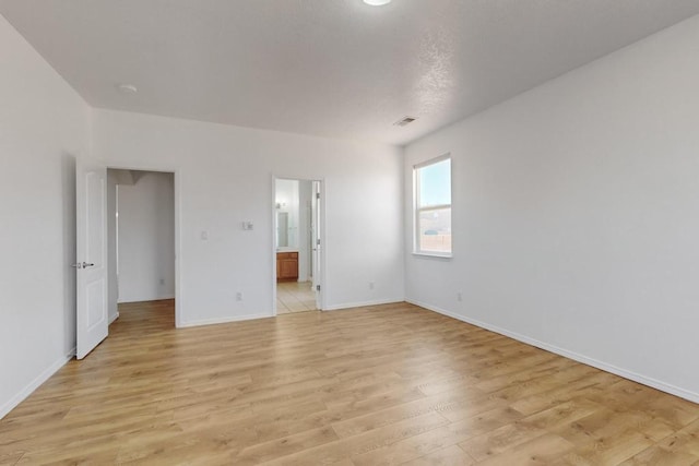 unfurnished bedroom featuring ensuite bath and light hardwood / wood-style floors