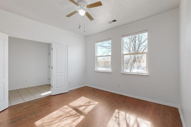 spare room with ceiling fan, light hardwood / wood-style floors, and a textured ceiling