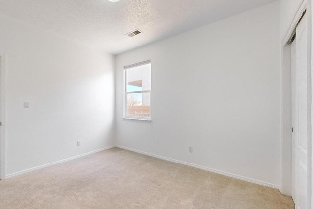 unfurnished bedroom with light colored carpet, a closet, and a textured ceiling