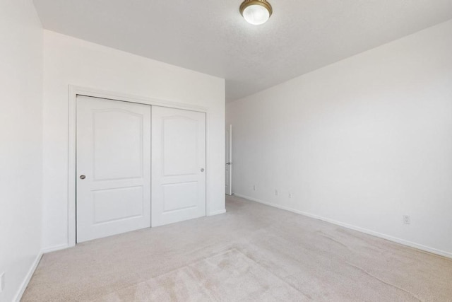 unfurnished bedroom with light colored carpet and a closet