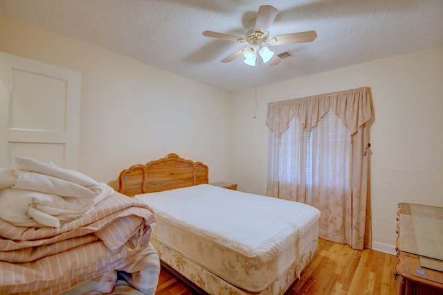 bedroom with hardwood / wood-style flooring, ceiling fan, and a textured ceiling