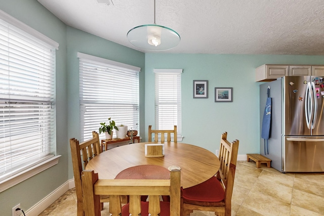 dining space featuring light tile patterned flooring and a textured ceiling