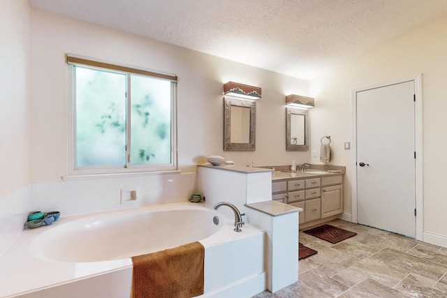 bathroom featuring vanity, a textured ceiling, and a washtub