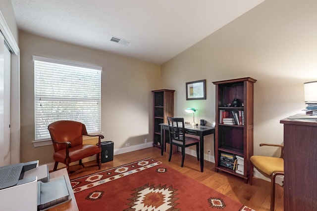 office area with hardwood / wood-style flooring and vaulted ceiling