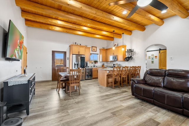 living room featuring beamed ceiling, beverage cooler, ceiling fan, wood ceiling, and light hardwood / wood-style flooring