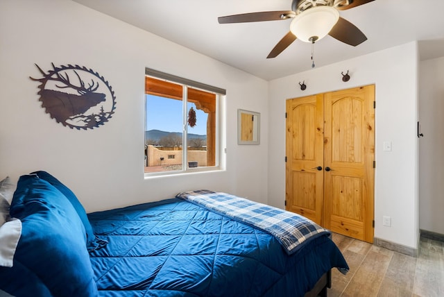 bedroom with ceiling fan, light hardwood / wood-style floors, and a closet