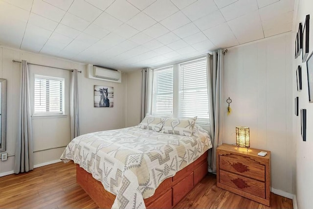 bedroom featuring wood-type flooring and a wall mounted air conditioner