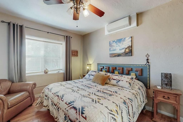 bedroom with hardwood / wood-style flooring, ceiling fan, and a wall mounted air conditioner