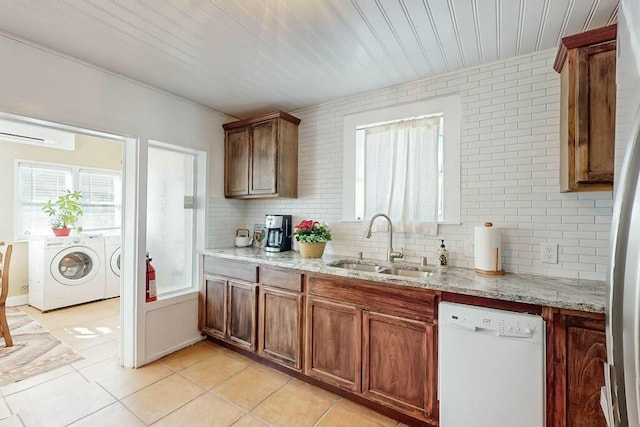 kitchen featuring sink, dishwasher, independent washer and dryer, light stone countertops, and decorative backsplash