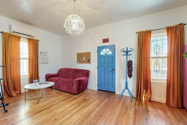 sitting room with a wealth of natural light, a wall mounted AC, and light hardwood / wood-style floors