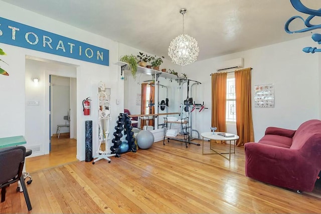 exercise room featuring a chandelier, a wall mounted AC, and hardwood / wood-style floors