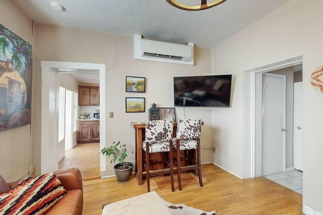 living room with an AC wall unit and light hardwood / wood-style floors