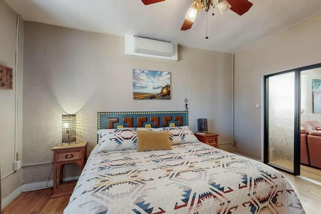 bedroom featuring ceiling fan, light hardwood / wood-style floors, a wall unit AC, and access to outside