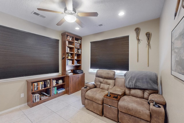 sitting room featuring a textured ceiling, ceiling fan, and light tile patterned flooring