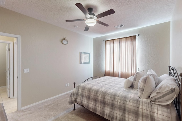 bedroom featuring ceiling fan, light colored carpet, and a textured ceiling