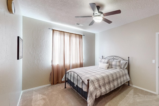 bedroom featuring light carpet, ceiling fan, and a textured ceiling