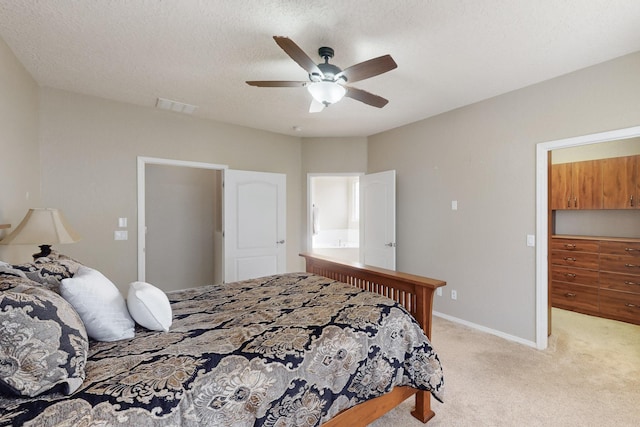 bedroom with ceiling fan, a spacious closet, light colored carpet, and a textured ceiling