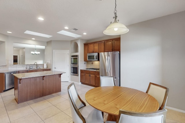 kitchen with tasteful backsplash, kitchen peninsula, pendant lighting, stainless steel appliances, and light stone countertops