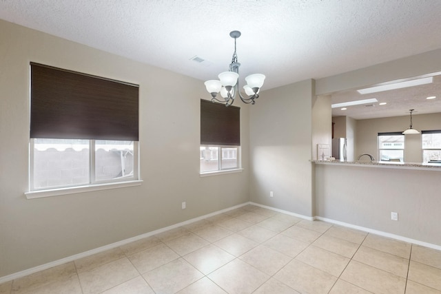 tiled spare room with a chandelier and a textured ceiling