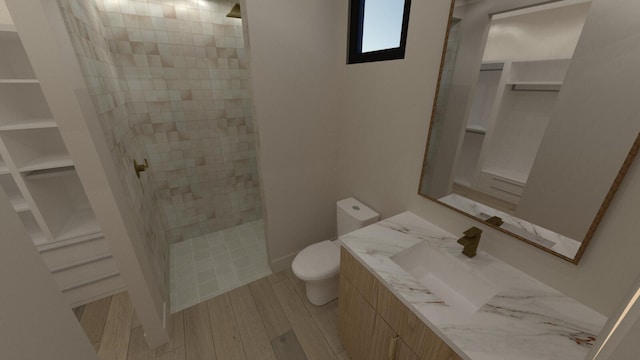 bathroom featuring vanity, wood-type flooring, toilet, and tiled shower